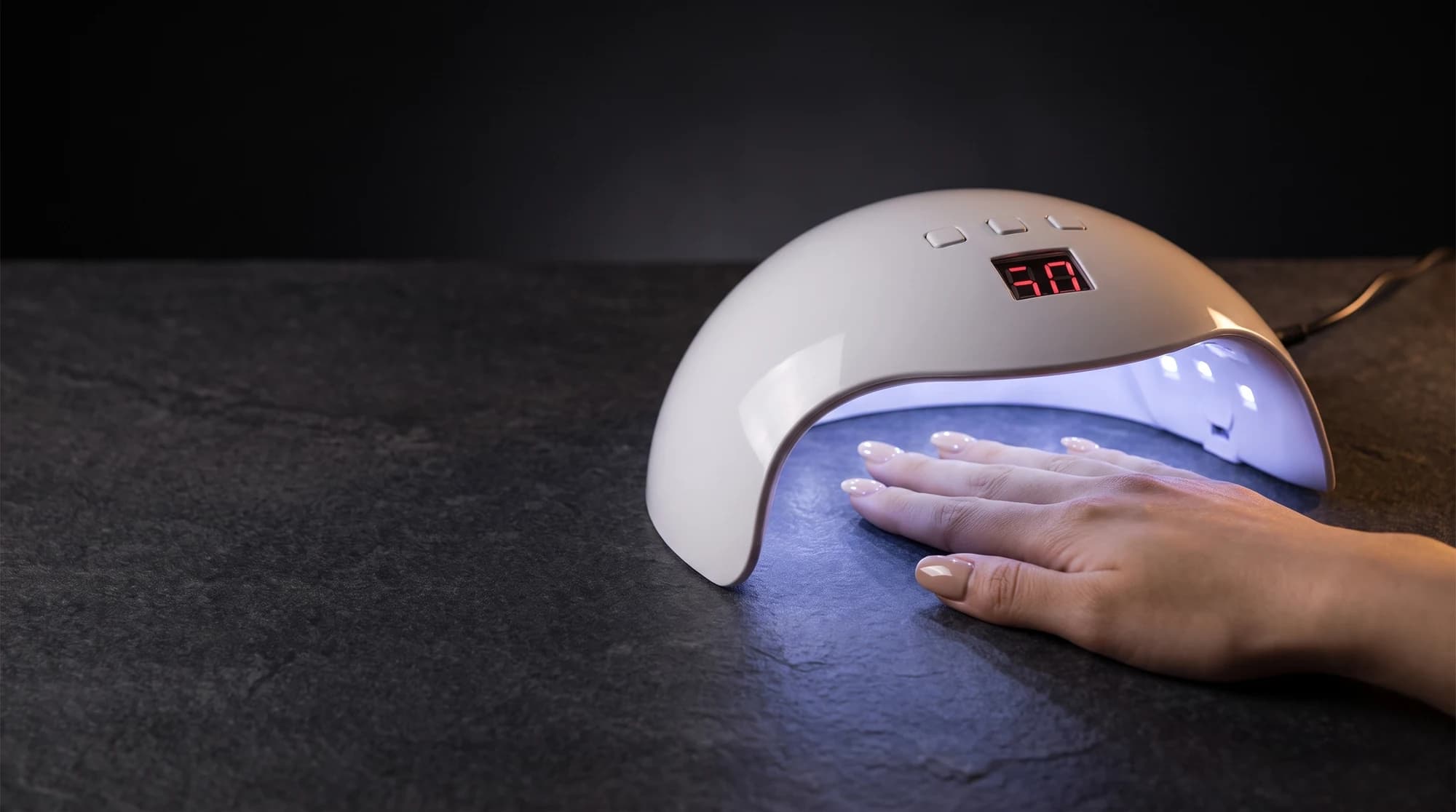 Main aux ongles nude glissée dans la lampe UV LED 48W Lunanails allumée