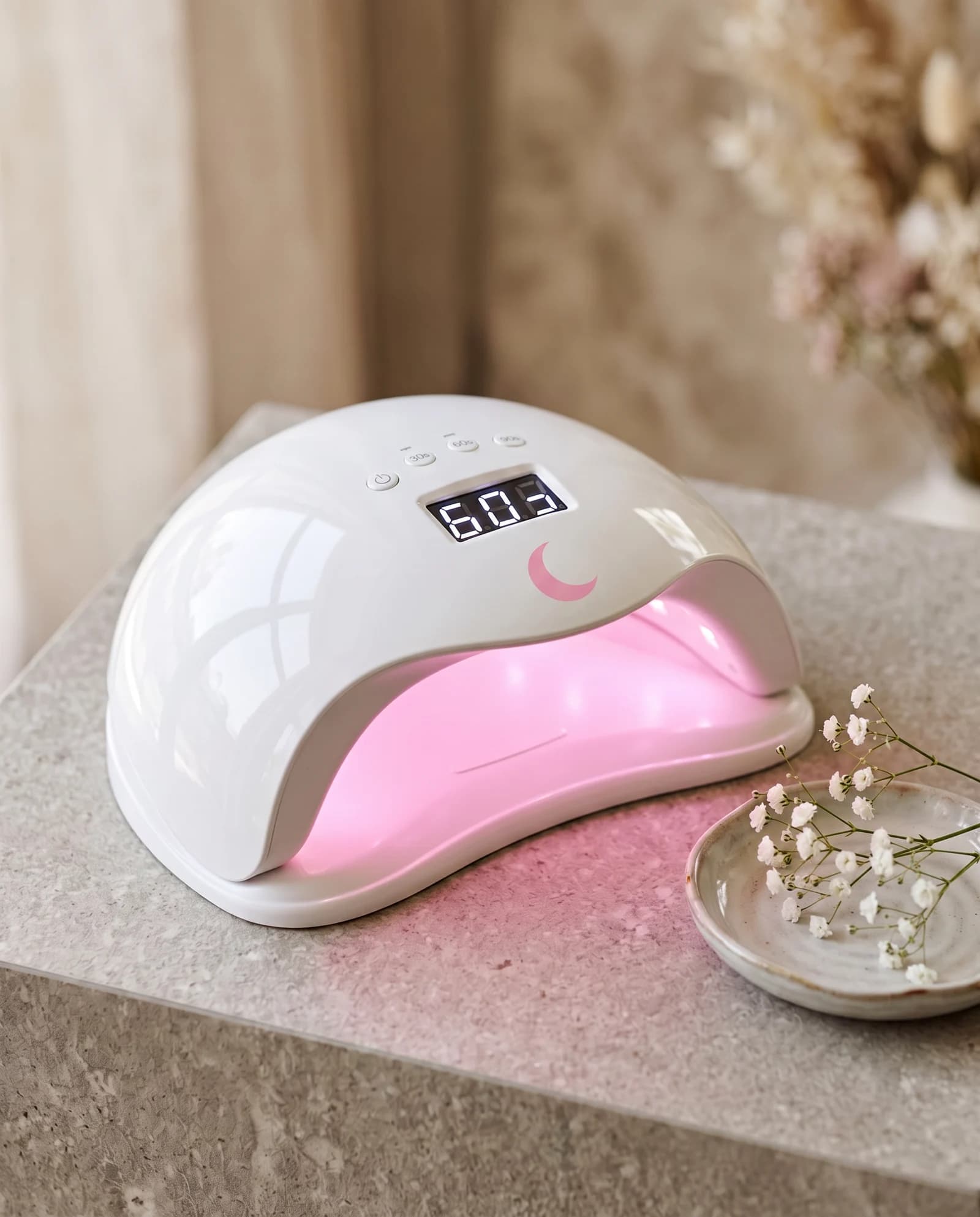 Lampe UV LED 48W Lunanails posée sur une table en pierre, lumière rose allumée